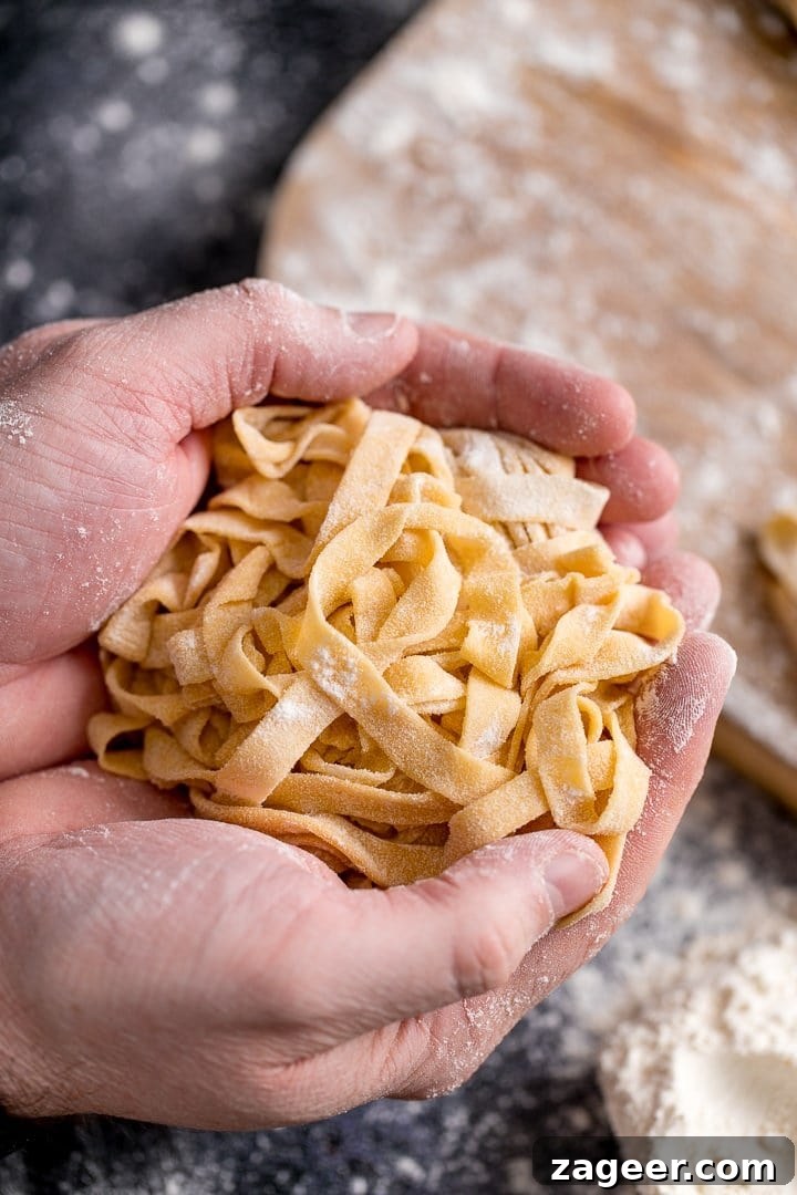Homemade tagliatelle cupped in two hands, showing its fresh texture.