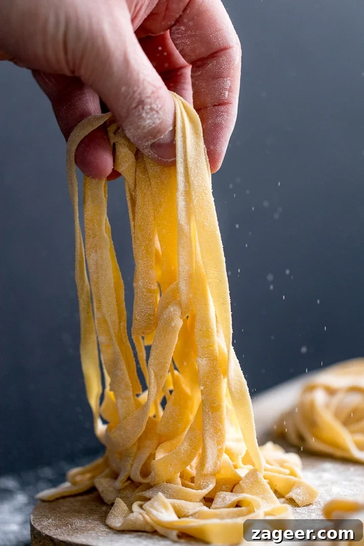 Homemade tagliatelle being lifted off a board, showcasing its freshness.