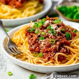 A delicious plate of spaghetti bolognese, beautifully presented on a light background, highlighting the rich sauce and perfectly cooked pasta.