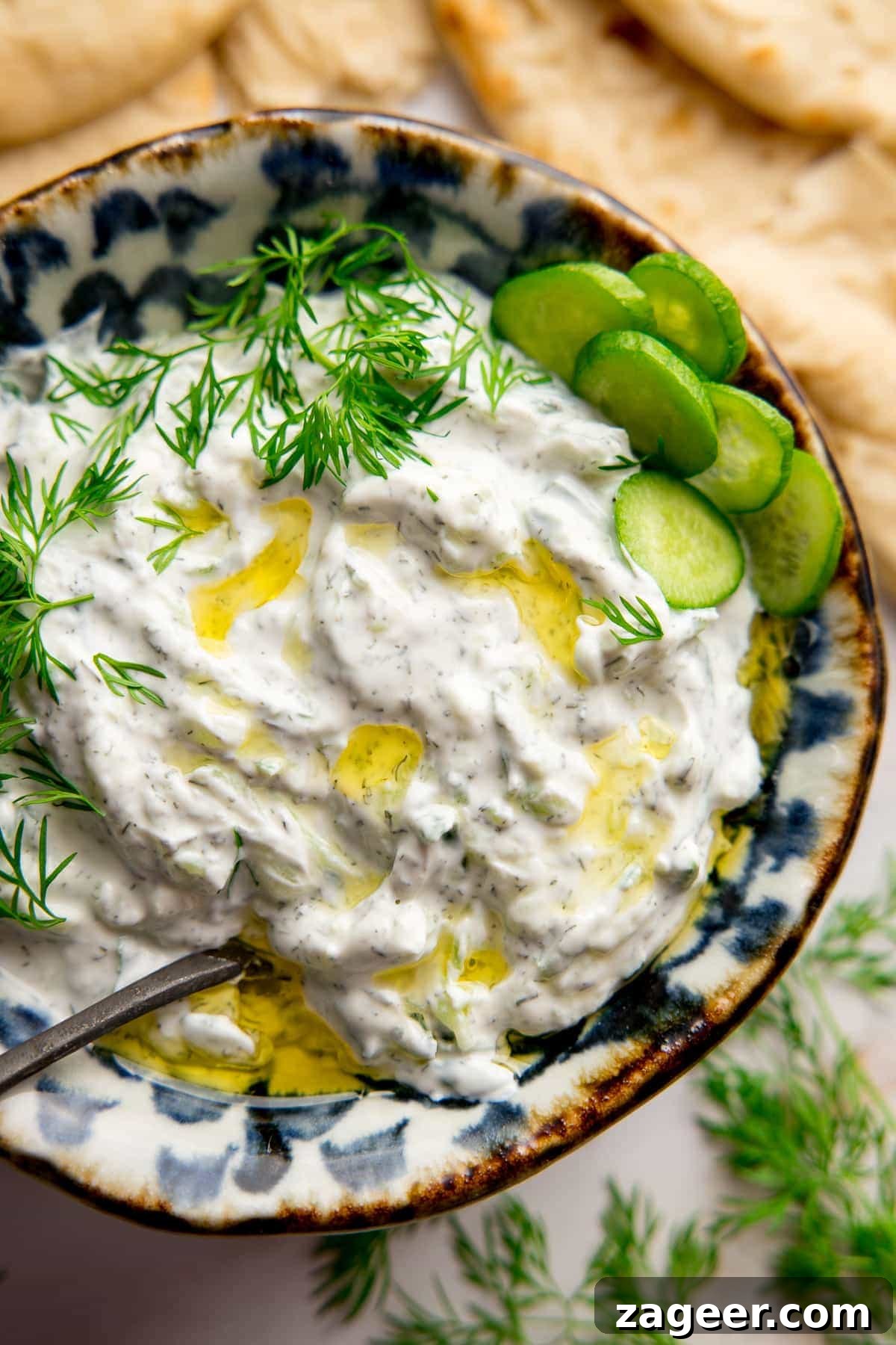 Whip Up Authentic Greek Tzatziki at Home 2 A beautifully presented bowl of homemade Tzatziki on a light background, garnished with fresh dill and a drizzle of olive oil, ready to be served.