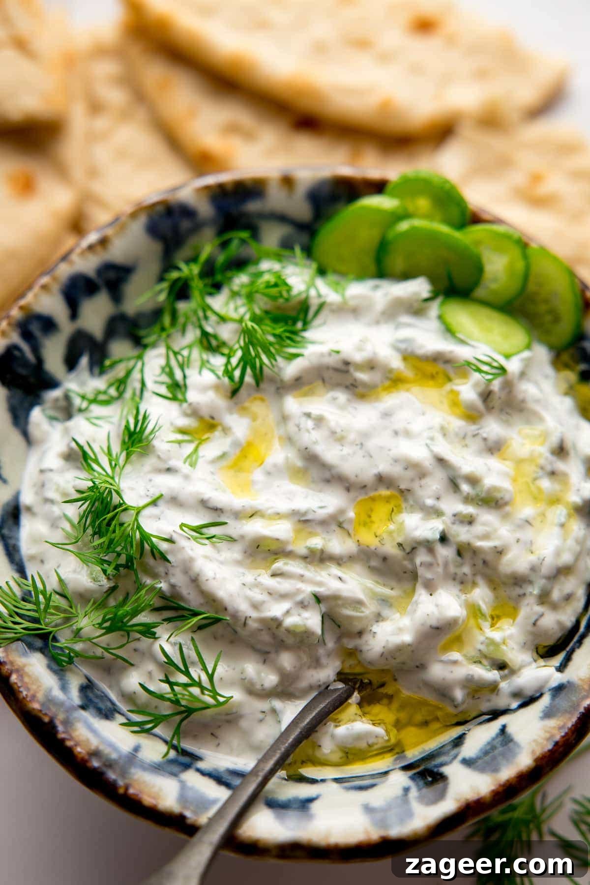 Whip Up Authentic Greek Tzatziki at Home 5 A bowl of fresh Tzatziki served with warm flatbreads, garnished with fresh dill and a drizzle of olive oil, ready for dipping.