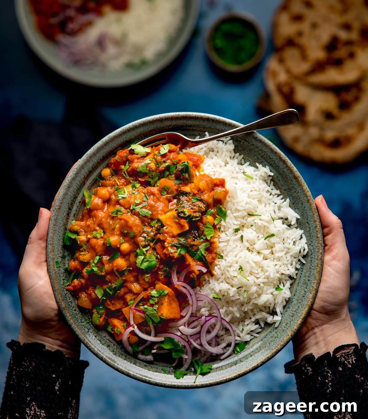 Golden Chickpea Sweet Potato Medley 6 Two hands gently holding a vibrant bowl of chickpea and sweet potato curry with rice, signifying warmth and comfort.