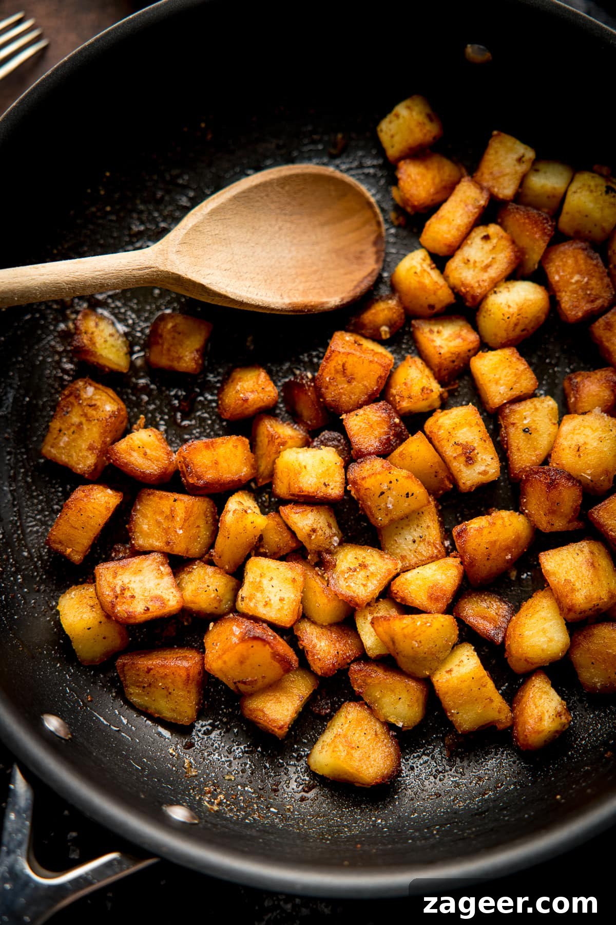 Garlic Sautéed Potatoes 5 saute potatoes in a dark pan with a wooden spoon
