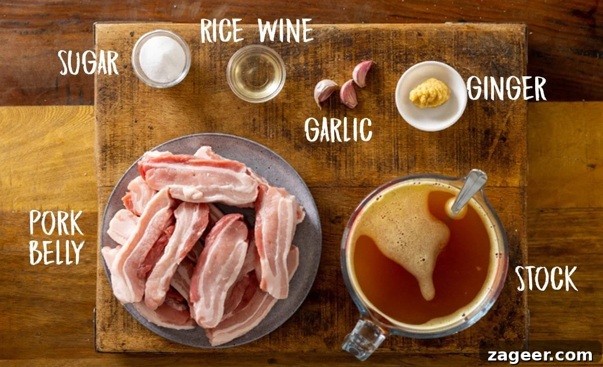 Ingredients for slow cooked pork belly on a wooden table, including pork belly slices, chicken stock, ginger, garlic, rice wine, and caster sugar.