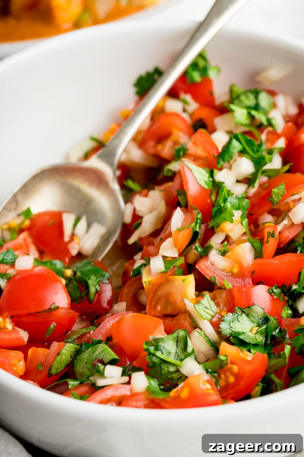 Garden Tomato and Onion Medley 6 Close-up view of the refreshing Indian Tomato and Onion Salad in a white bowl with a spoon, highlighting its juicy, crunchy texture.