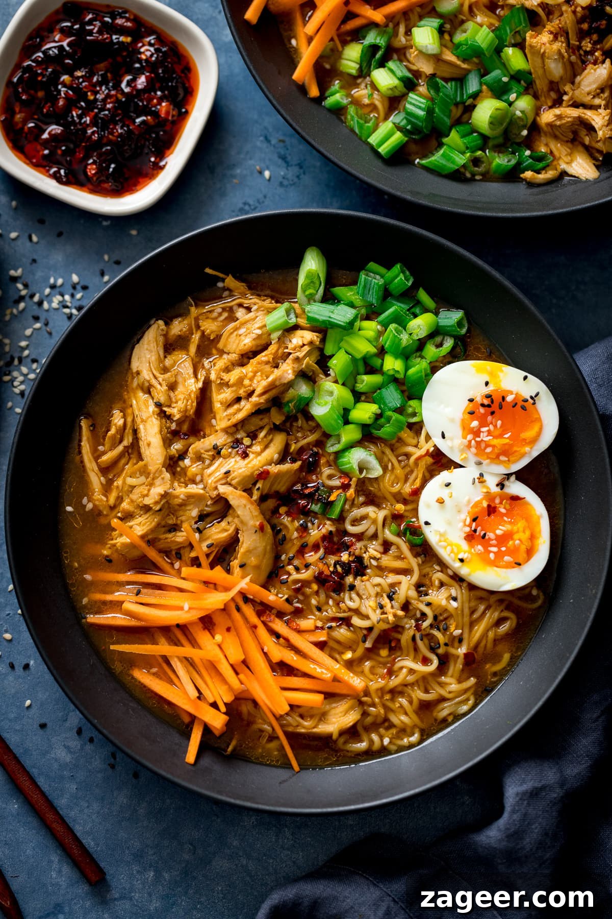 Effortless Chicken Ramen in 20 Minutes 2 Overhead view of quick chicken ramen in a black bowl, garnished with a perfect soft-boiled egg, vibrant spring onions, and crisp carrot strips.