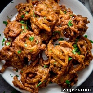 Crispy Golden Onion Bhaji 7 Onion bhajis on a white plate, sprinkled with coriander.