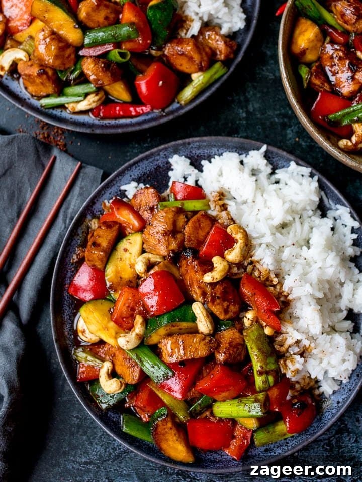 Szechuan Chili Peanut Chicken 2 Panda Express style Kung Pao Chicken served on a dark plate with steamed rice, garnished with fresh scallions.