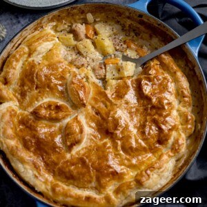 Square image of a sausage and mustard pie - shot from overhead. There is a spoonful of the pie filling being taken out.