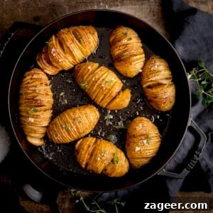 Hasselback potatoes in a black cast iron pan on a wooden table next to a dark grey napkin.