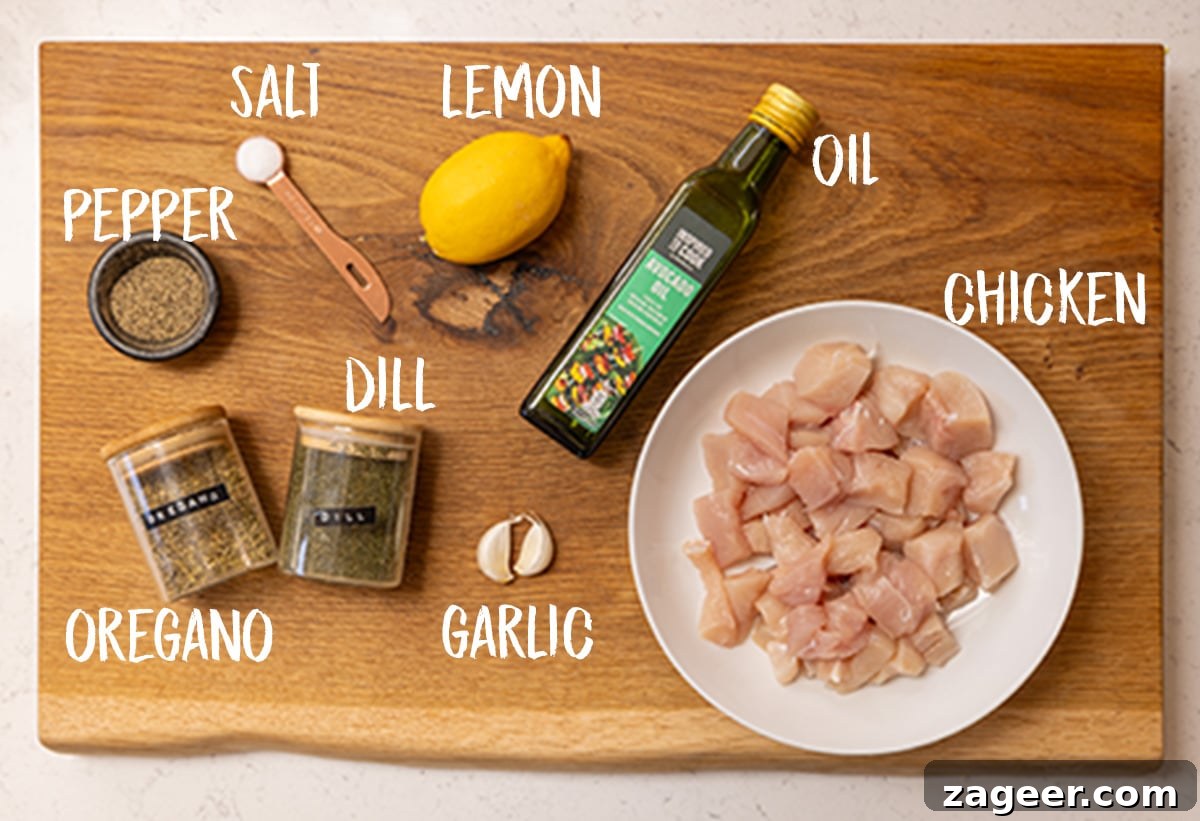 Lemon Herb Air Fryer Greek Chicken 3 Ingredients for air fryer Greek chicken laid out on a rustic wooden board, including chicken breast, lemon, garlic, and various herbs.