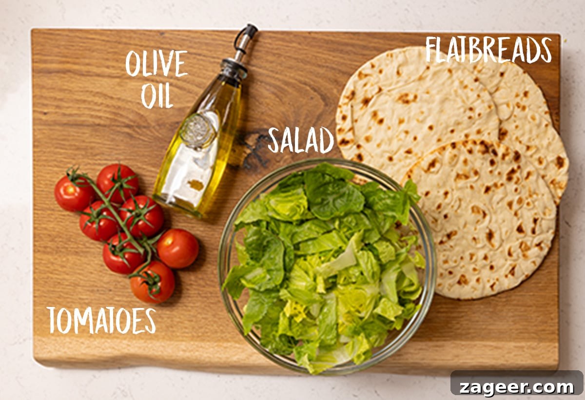 Lemon Herb Air Fryer Greek Chicken 5 A wooden board showcasing fresh flatbreads, a small bowl of olive oil, vibrant chopped tomatoes, and crisp shredded lettuce, all perfect components for a Greek chicken wrap.