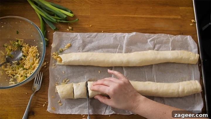 The Secret to Vegetarian Sausage Rolls That Meat Eaters Crave 11 A sharp knife slicing a long vegetarian sausage roll into perfectly bite-sized pieces, ready for the oven.
