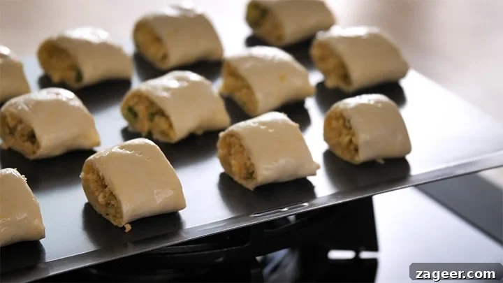 The Secret to Vegetarian Sausage Rolls That Meat Eaters Crave 12 A baking tray filled with neatly arranged, unbaked vegetarian sausage rolls, brushed with egg wash and ready to be placed into a hot oven.