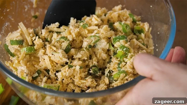 The Secret to Vegetarian Sausage Rolls That Meat Eaters Crave 5 The savory filling for vegetarian sausage rolls, a mix of cheese, breadcrumbs, spring onions, and spices, being gently combined in a bowl.