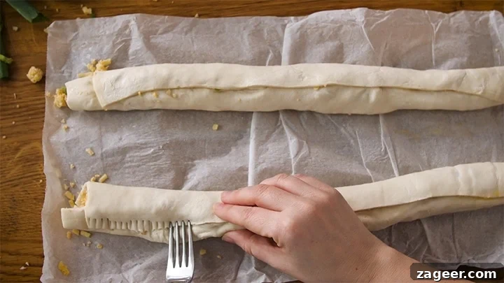 The Secret to Vegetarian Sausage Rolls That Meat Eaters Crave 9 A fork being used to press and seal the pastry seam of a vegetarian sausage roll, ensuring a secure closure before baking.