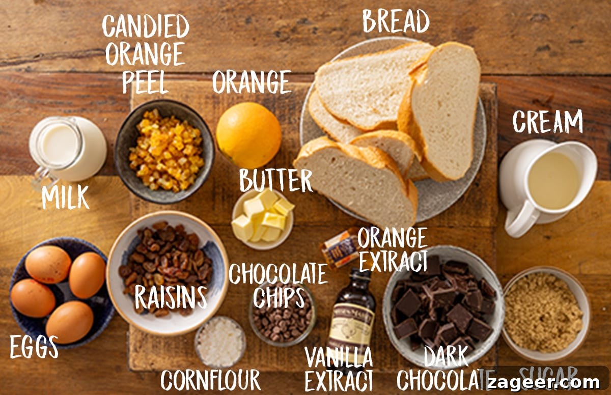 Ingredients for chocolate orange bread and butter pudding on a wooden board, including bread, butter, candied peel, sultanas, milk, cream, vanilla, egg yolks, brown sugar, cornflour, orange extract, dark chocolate, chocolate chips, and an orange.