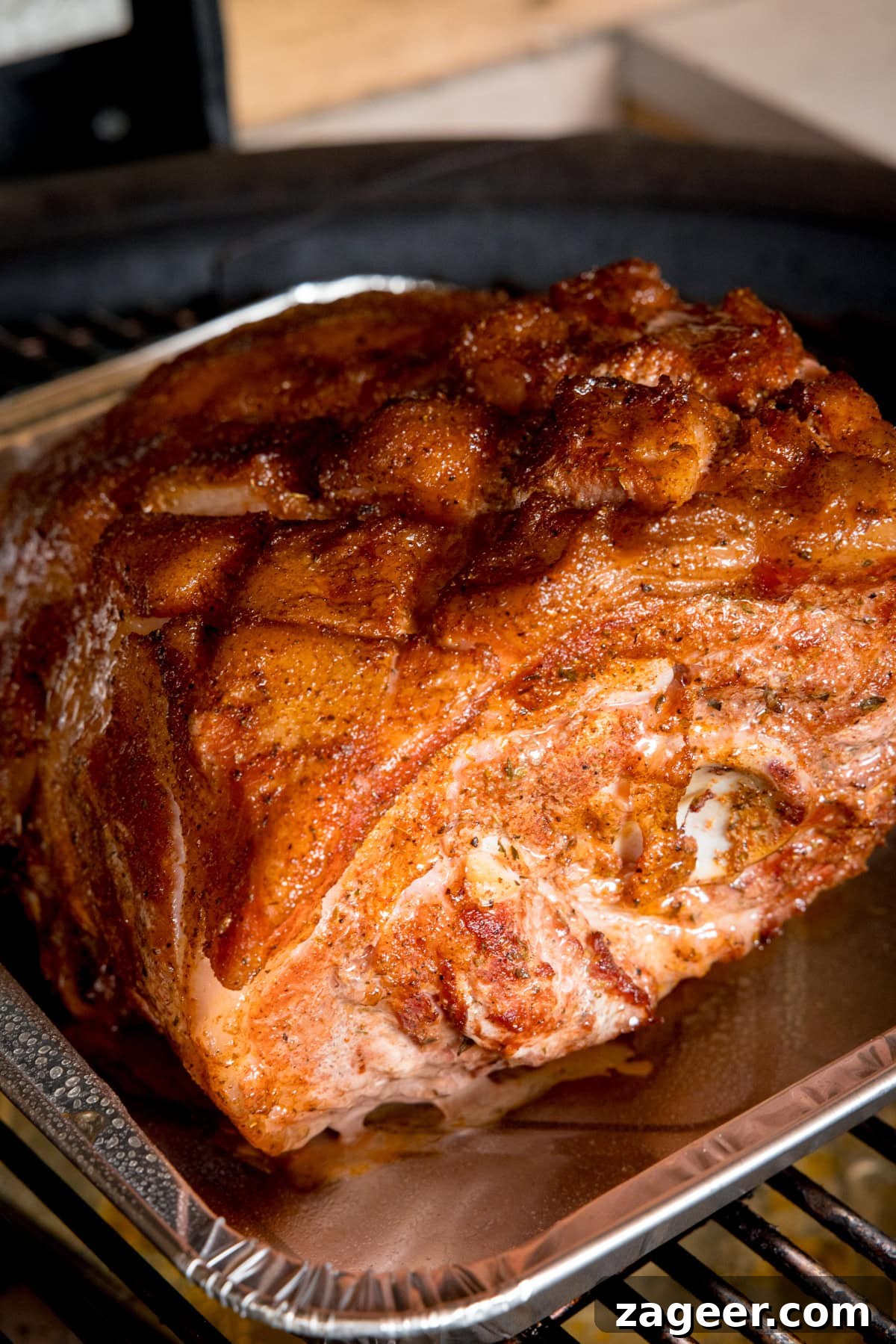Slow-Cooked BBQ Pork Perfection 4 A tall image of a prep step in BBQ Pulled Pork. The cut of pork is cooked and on a silver tray in the middle of the image. The silver tray is on top of a black BBQ.