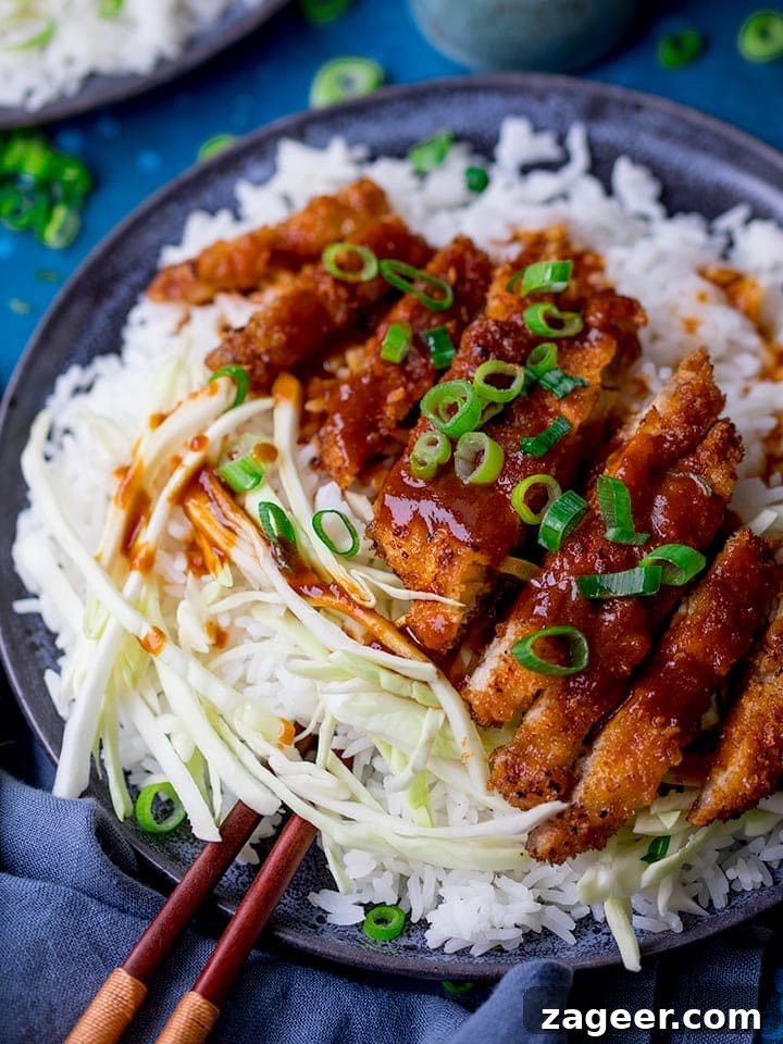 Fiery Crispy Tonkatsu 6 Tonkatsu pork curry on a plate with rice and cabbage. Spring onions sprinkled on top.