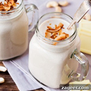 White Chocolate Coconut Cashew Hot Smoothie in a glass jar, garnished with toasted coconut flakes