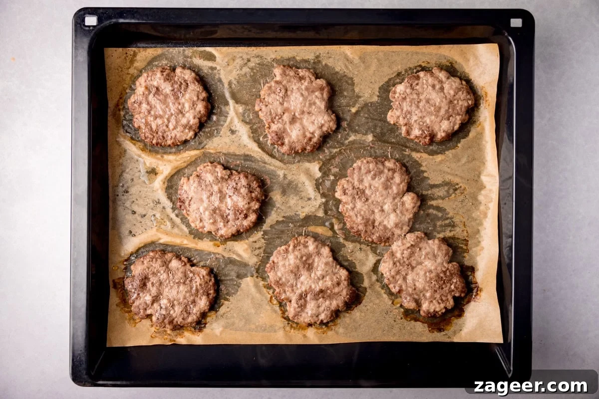 Meal Prep Powerhouse: Homemade High Protein Sausage and Egg McMuffin 6 Golden brown, cooked sausage patties on a baking sheet.