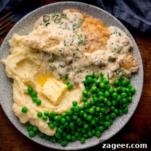 Plate with lemon butter sea bream in creamy sauce, mashed potatoes with butter, and green peas on a grey dish.