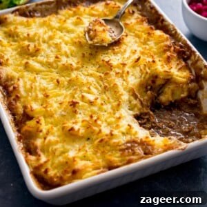 Shepherd's pie in a white dish with a portion taken out.