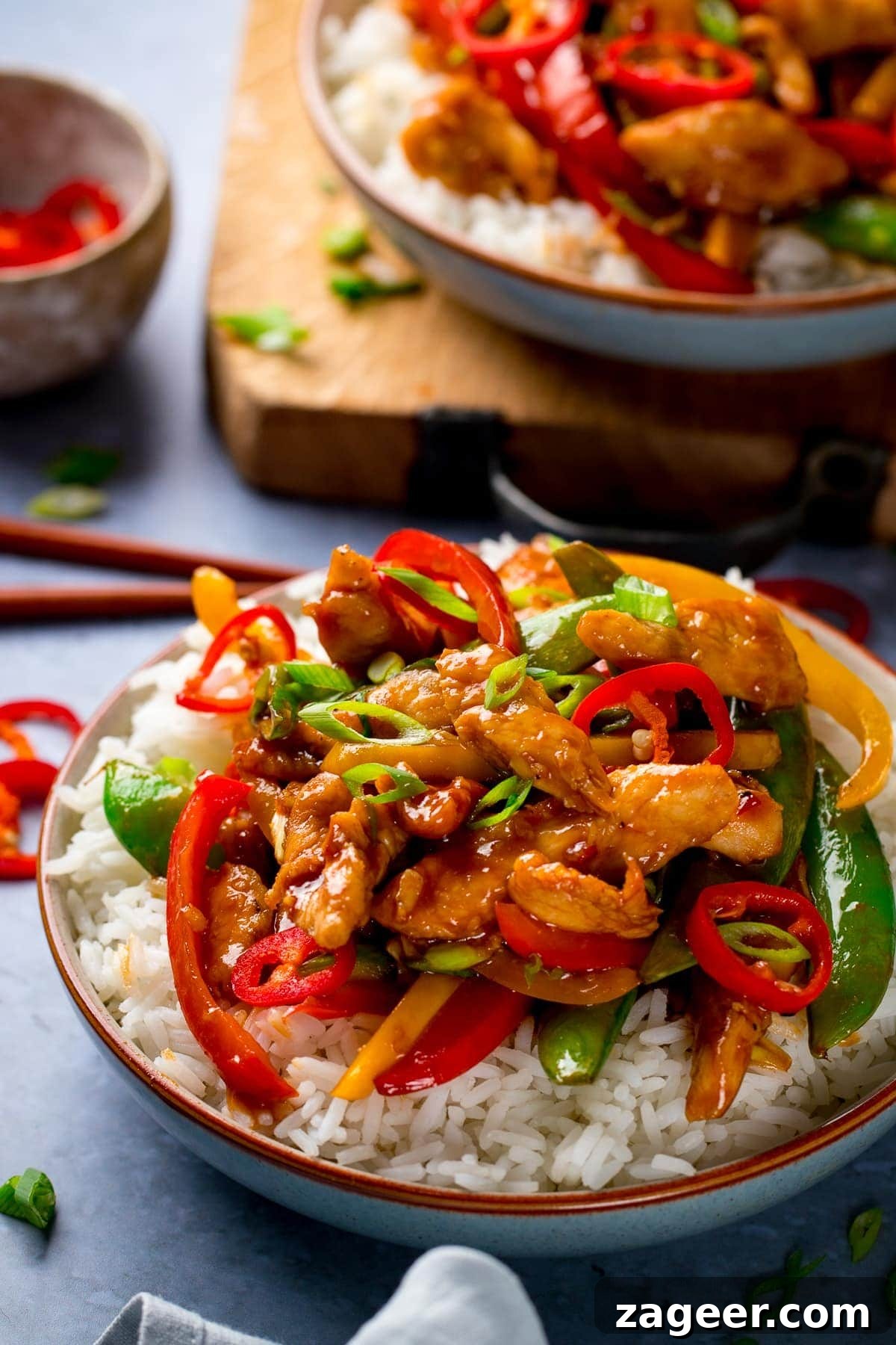 Fast & Flavorful Chicken Stir-Fry 2 Delicious chicken and veggie stir fry served with rice, garnished with fresh chillies and spring onions, ready to be enjoyed as a quick and healthy meal.