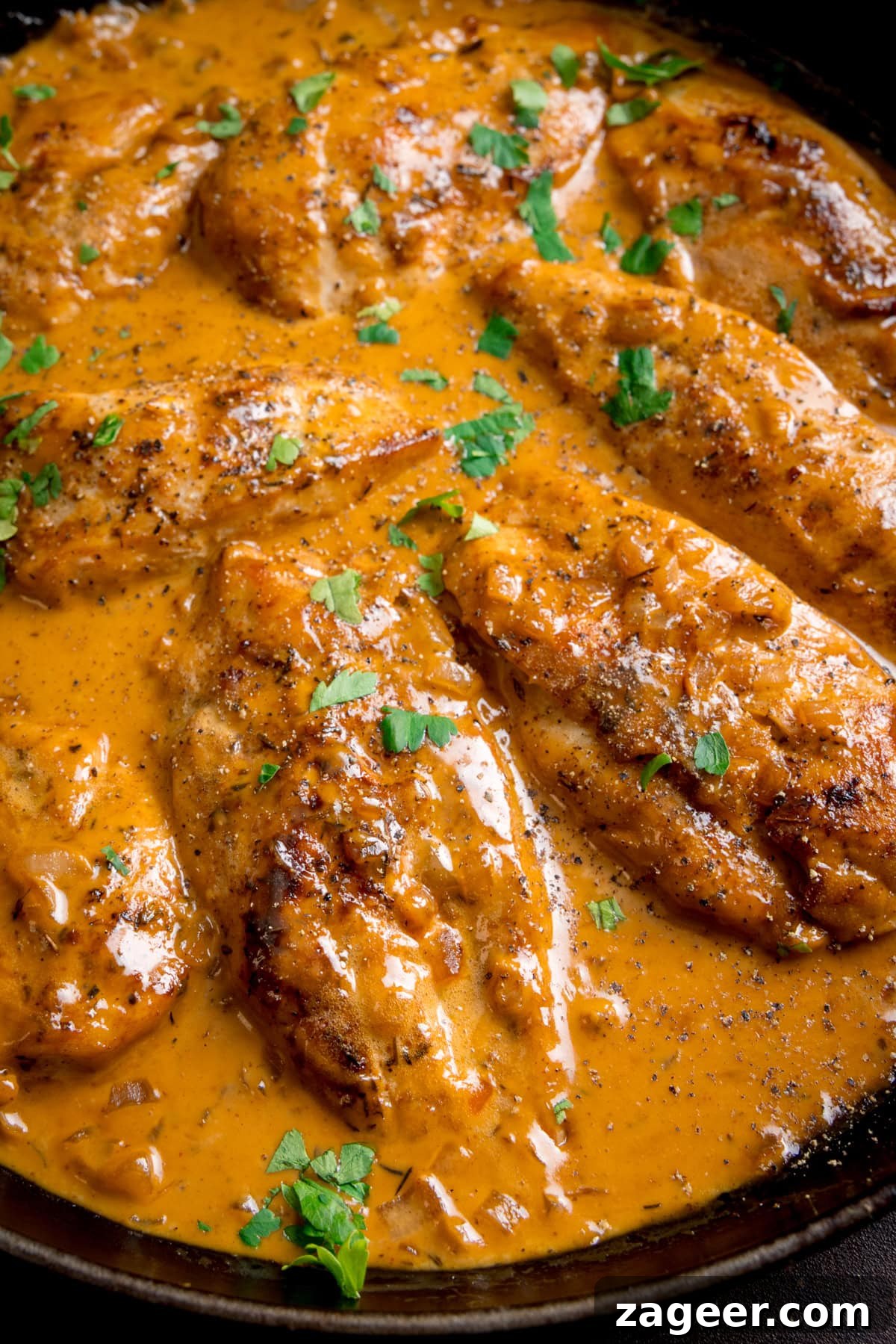 Golden Glazed Honey Mustard Chicken 2 Chicken breasts cooked in a creamy honey mustard sauce, garnished with chopped parsley and black pepper, served in a frying pan.