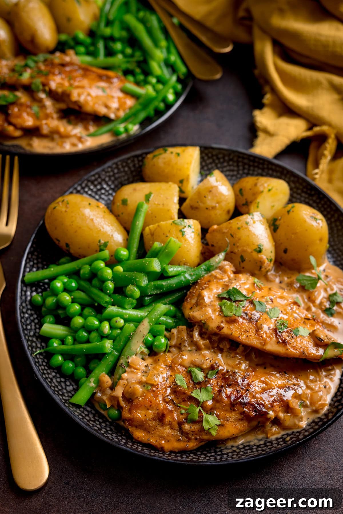 Golden Glazed Honey Mustard Chicken 6 A plate with chicken in creamy honey mustard sauce, boiled potatoes, green beans, and peas, garnished with parsley.