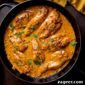 Golden Glazed Honey Mustard Chicken 7 Creamy honey mustard chicken topped with chopped parsley in a black frying pan.