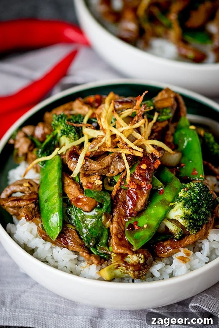 Sizzling Ginger Beef Stir Fry 2 A beautifully presented bowl of Spicy Ginger Beef Stir Fry, featuring tender slices of beef, bright green broccoli florets, and a generous topping of golden crispy ginger, served alongside fluffy white rice. This mouth-watering dish is perfect for a quick and healthy dinner.