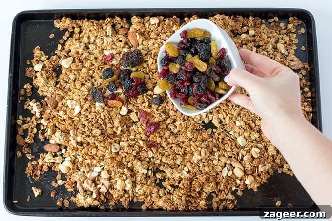 Wholesome Berry Nut Granola 3 dried fruits being tipped onto a tray of granola