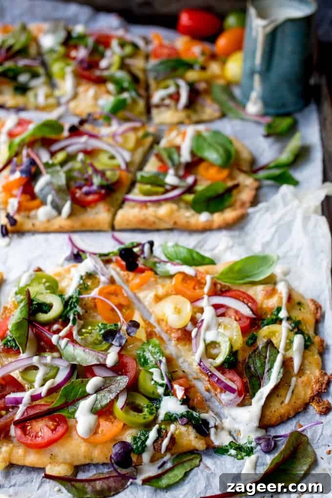 Summer Tomato Pizza with Basil Garlic Butter (Vegetarian) 3 Close-up of a slice of Vegetarian Summer Tomato Pizza showcasing the colorful cherry tomatoes, basil, and creamy cashew drizzle. The golden-brown flatbread crust is visible, promising a delightful texture.
