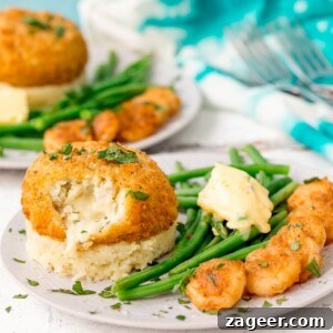Golden Saucy Fish Co. Fishcakes on a bed of cheesy mashed potatoes, with crispy garlic prawns and vibrant green beans, garnished with fresh parsley.