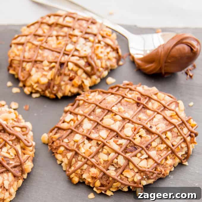 Gluten-Free Hazelnut Nutella Cookies Recipe 3 Gluten Free Hazelnut Nutella Cookies - Soft oat flour chocolate biscuits, rolled in hazelnuts and filled with a gooey chocolate centre.