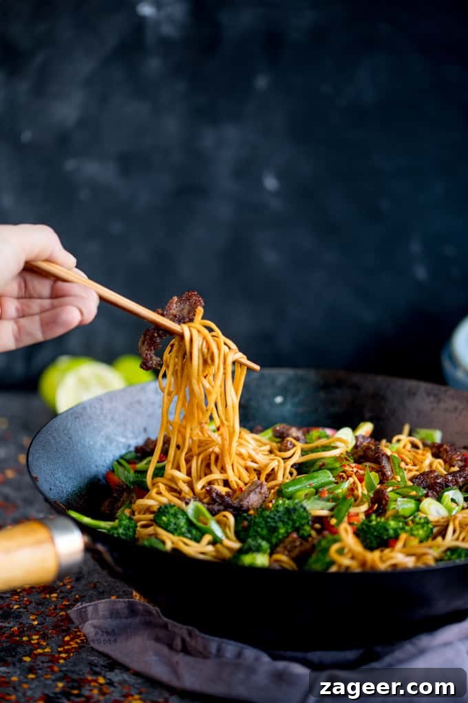 Crispy Chili Beef Noodles Recipe for Flavorful Weeknight Dinner 5 Side-on image of crispy chilli beef noodles with broccoli and peppers in a wok.