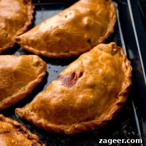 Authentic Cornish Pasty Recipe: Traditional British Meat Pasty Guide 14 Cornish pasties on a black baking tray