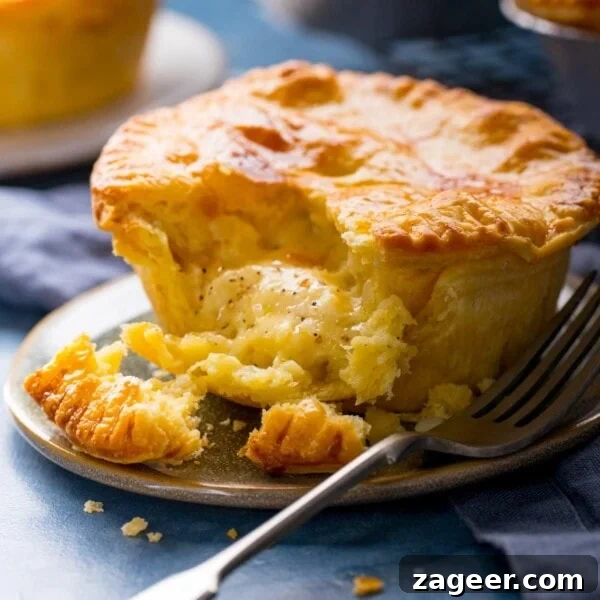 Authentic Cornish Pasty Recipe: Traditional British Meat Pasty Guide 9 Square image of a small cheese and onion pie on a plate with a piece taken out.