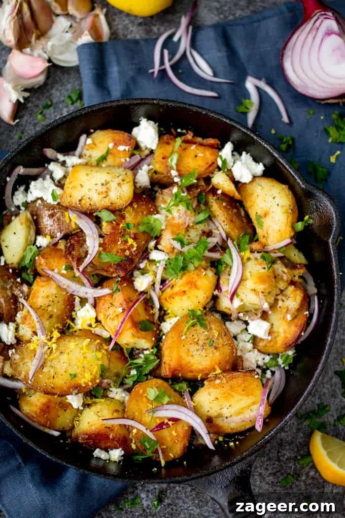 Greek-Style Potato Hash with Feta and Herbs 2 Overhead shot of crispy Greek style potatoes in a pan with feta, red onions, parsley and lemon zest. Ingredient scattered around.