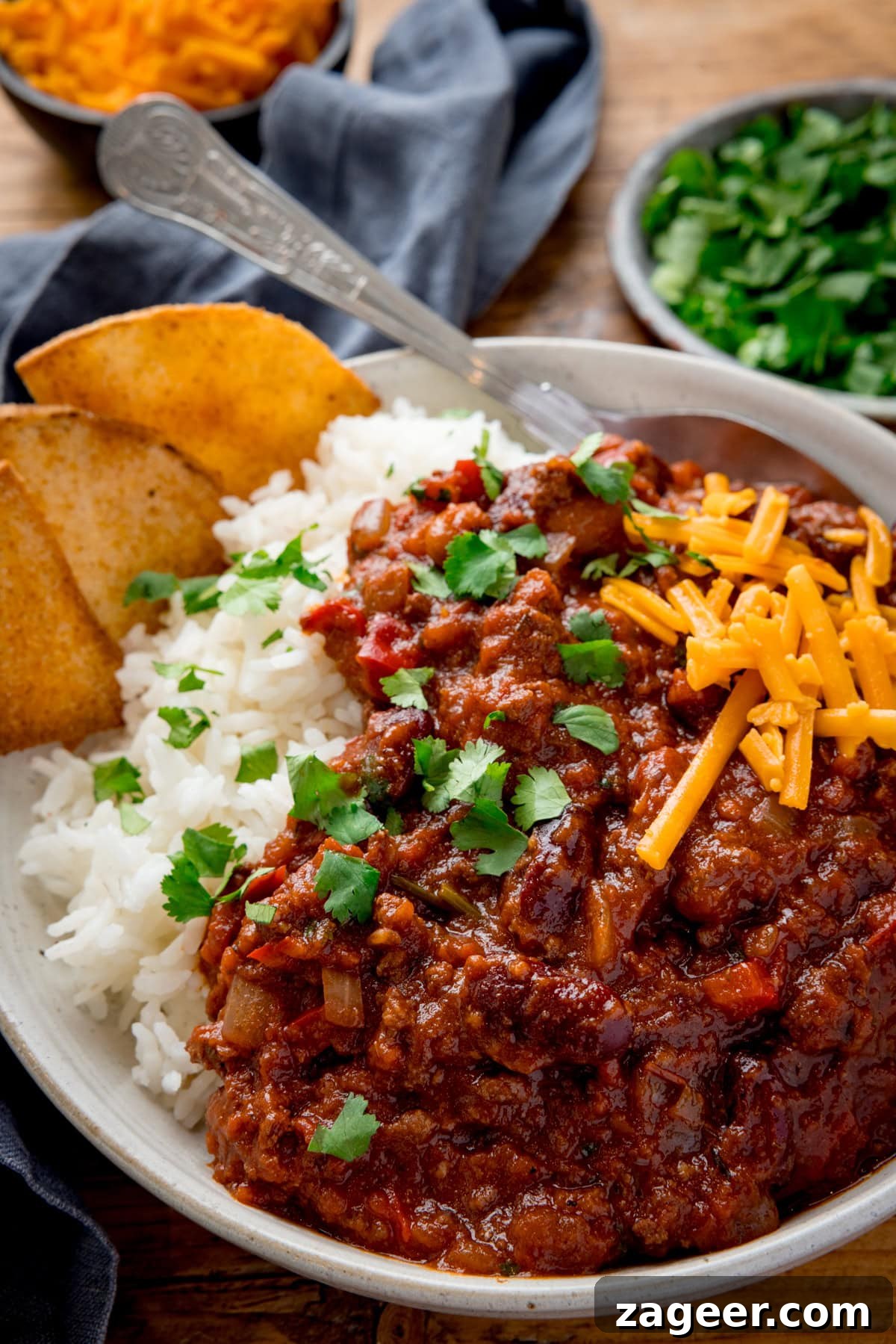 Authentic Chilli Con Carne Recipe with Smoky Beef and Beans 12 A bowl full of chilli con carne on a bed of white rice with a few freshly baked tortillas nestled in too.