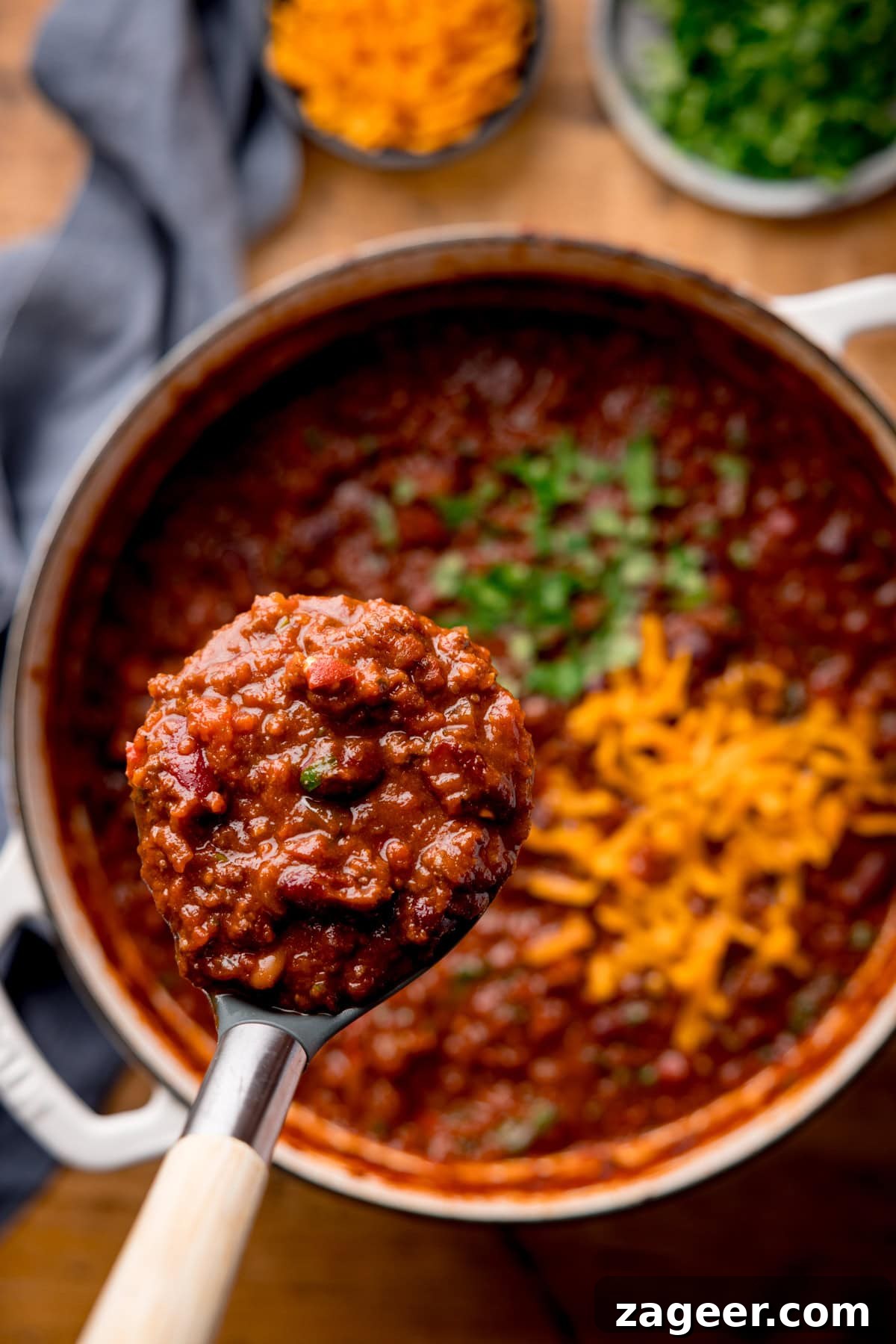 Authentic Chilli Con Carne Recipe with Smoky Beef and Beans 7 A close up of a ladle full of chilli being lifted from a pot full of chilli.