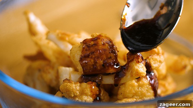 Asian-Style Baked Cauliflower Wings: Sticky Sesame Chili Recipe 6 Asian style sauce being poured over baked cauliflower florets