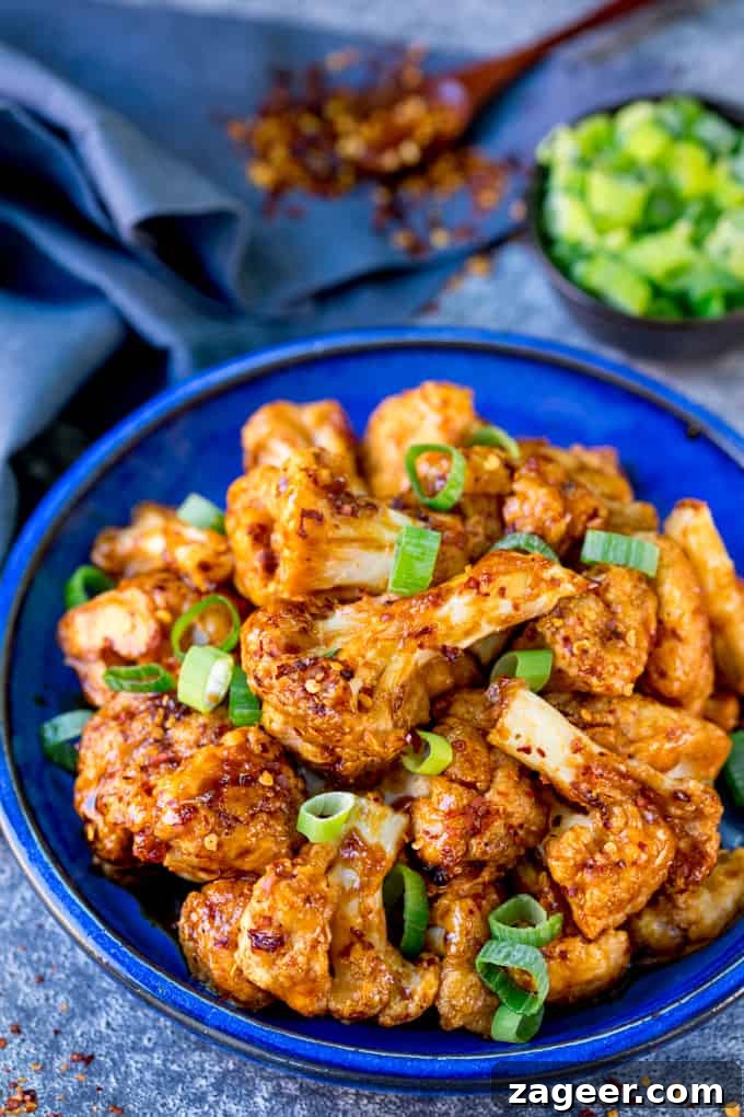 Asian-Style Baked Cauliflower Wings: Sticky Sesame Chili Recipe 7 Asian cauliflower wings on a blue plate with spring onions sprinkled on top