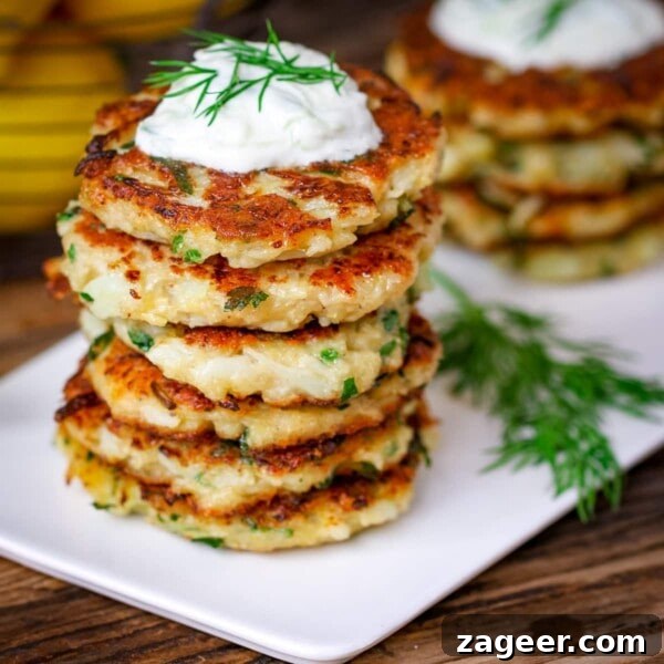 Asian-Style Baked Cauliflower Wings: Sticky Sesame Chili Recipe 9 Square image of a stack of cauliflower fritters topped with tzatziki on a white plate on a wooden board.