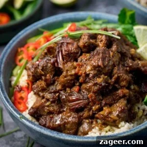 Beef rendang in a blue bowl with rice, chillies and greens