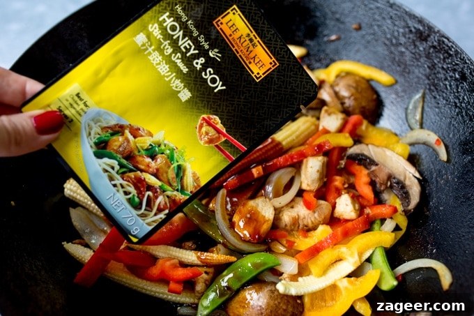 Honey-Soy Chicken Stir-Fry with Spicy Asian Noodles 7 Adding stir fry sauce to chicken and vegetables in a wok