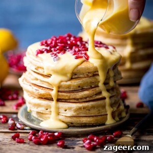 Lemon sauce being poured onto stack of pancakes