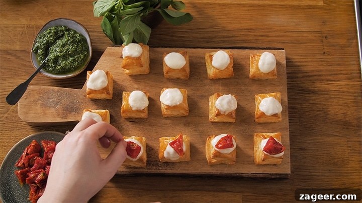 Caprese Puff Pastry Bites: Tomato, Basil & Mozzarella Appetizers 7 Placing sundried tomatoes on top of puff pastry squares with mozzarella