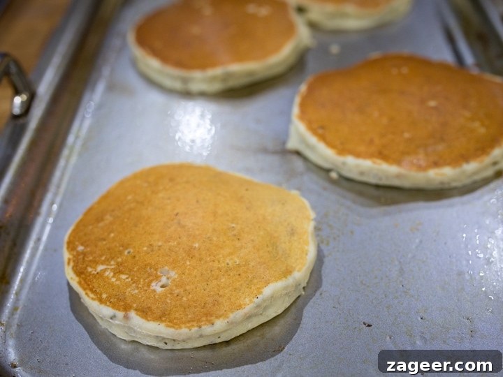 Gluten-Free Hazelnut Chia Pancakes with Blueberry Compote 6 Chia hazelnut pancakes cooking on a griddle - browned on top